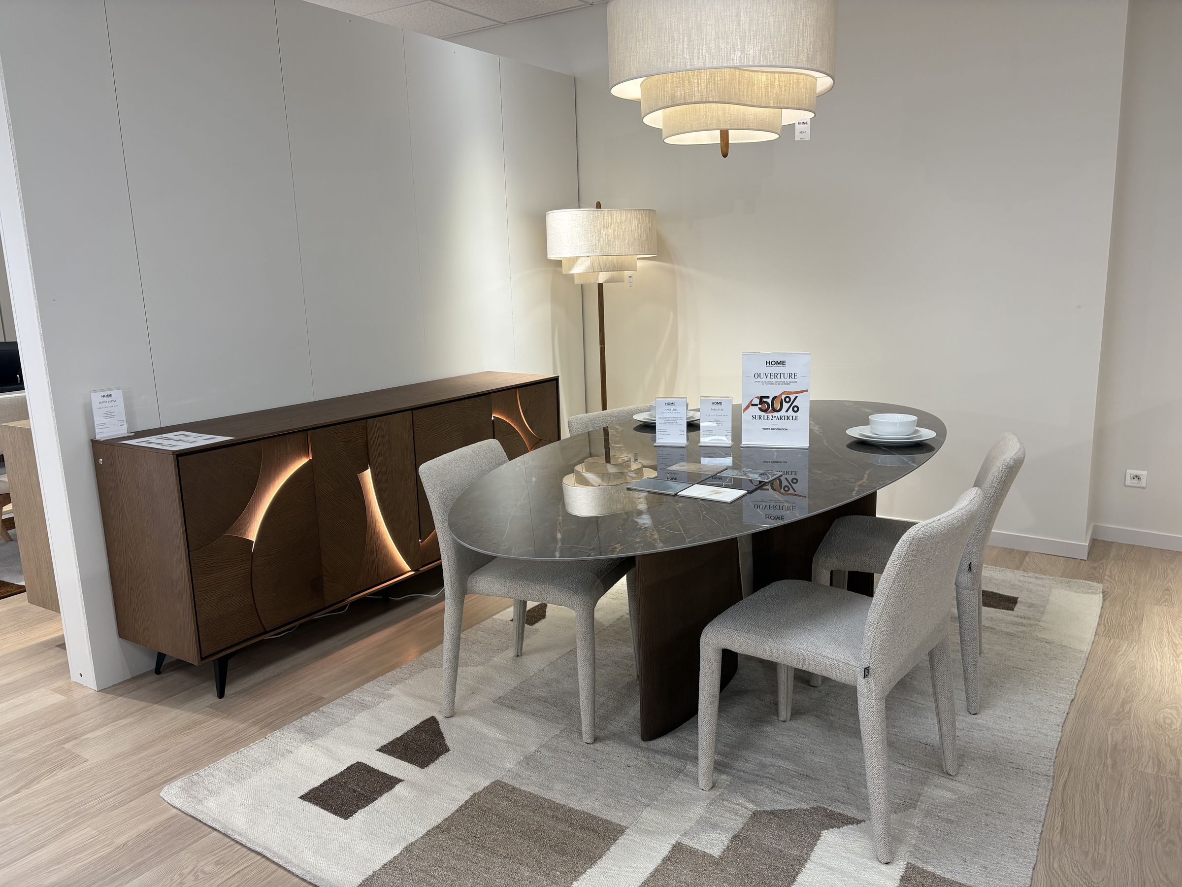 Table ovale en verre fumé, chaises claires et buffet en noyer rétro-éclairé